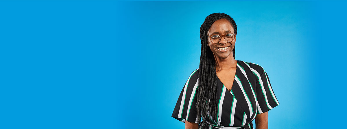 a young woman with long braided hair smiling at the camera in front of a blue background