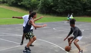Three young men play basketball on an outdoor court