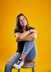A young woman sitting on a stool posing for the camera