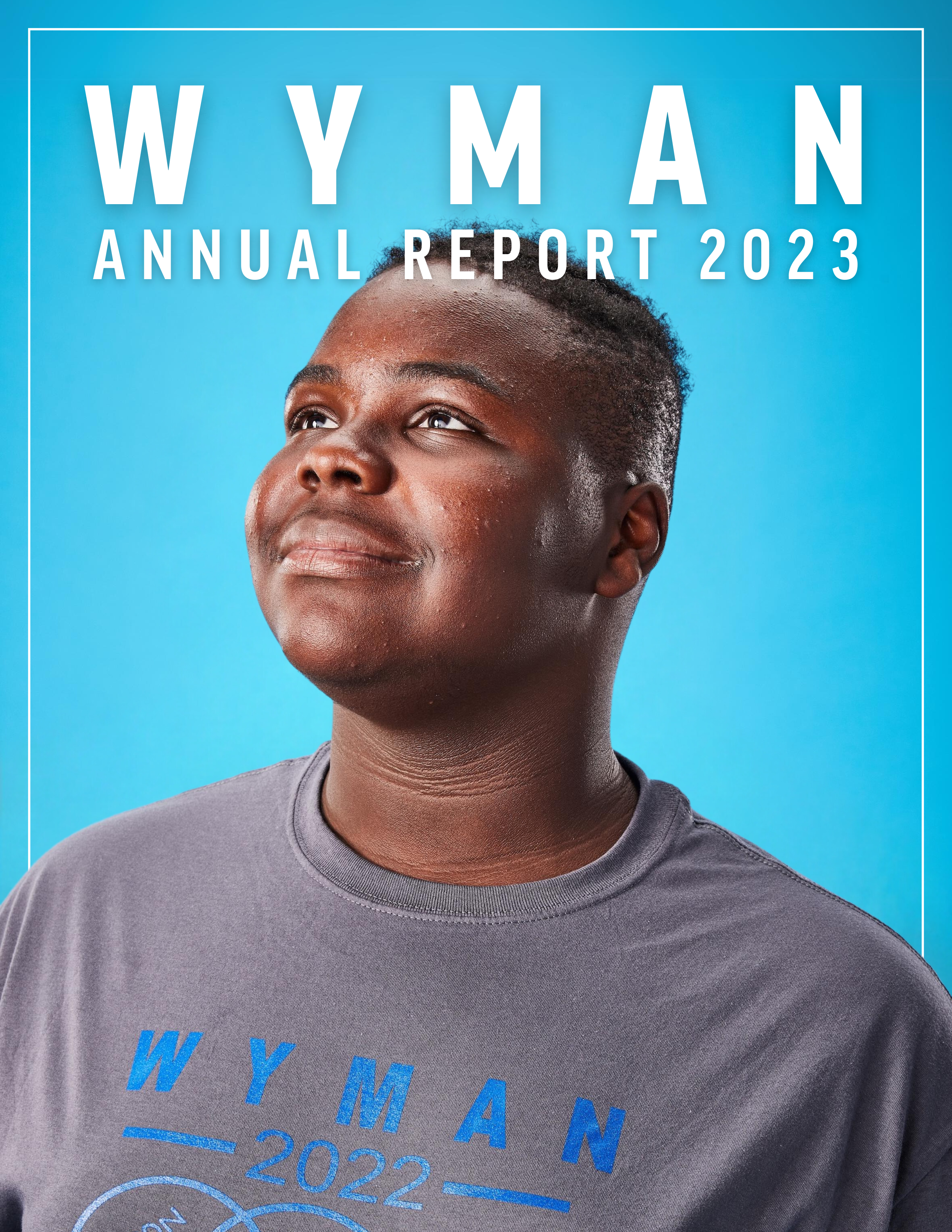 Wyman 2023 annual report front cover featuring a young man wearing a grey Wyman shirt smiling and staring up, in front of a blue background
