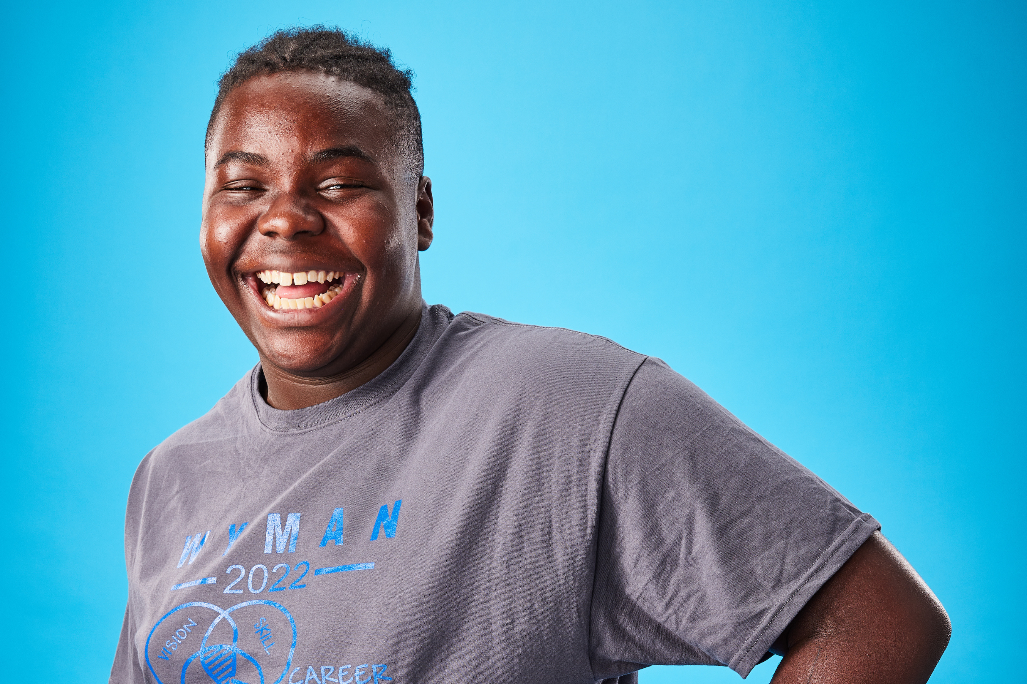 Young man poses in front of a blue background smiling