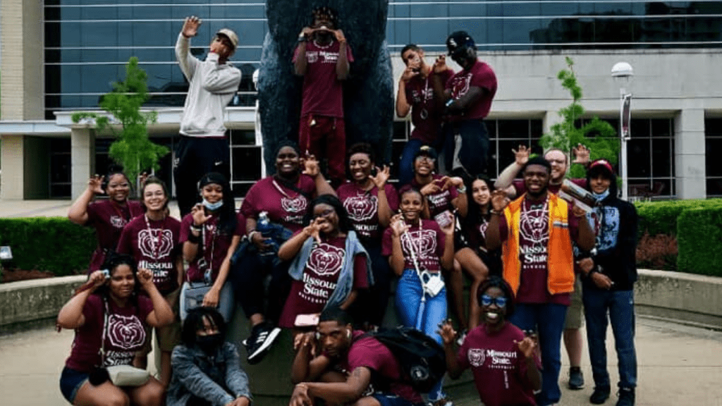 group of teens posing for the camera near a bear statue