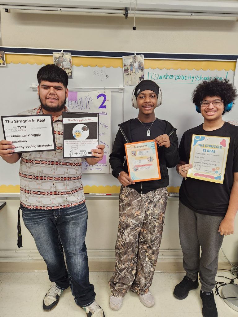 three young men stand holding signs they have made with uplifting messages