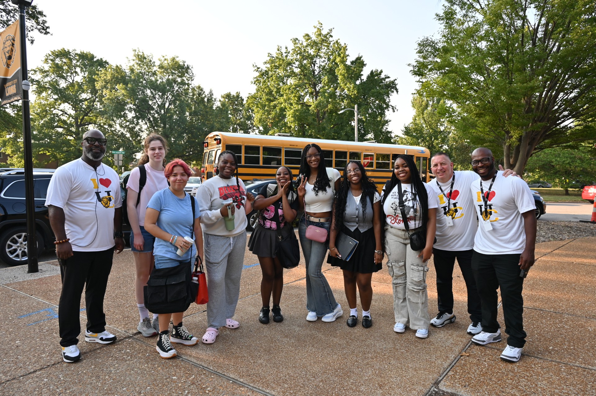 group of students and teachers posing in front of school bus